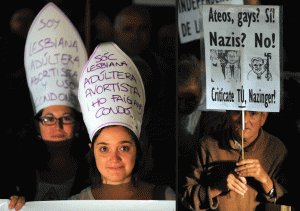 Protesta LGTB por la visita del Papa y manifestantes con carteles en otra protesta en España