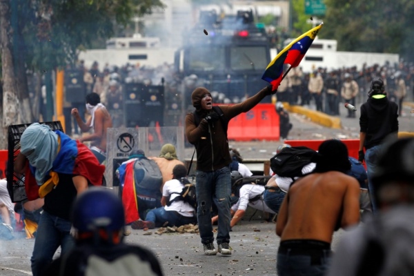 Anti-government protesters clash with police in Caracas March 12, 2014. Supporters and foes of Venezuelan President Nicolas Maduro took to the streets of Caracas again on Wednesday a month after similar rival rallies brought the first bloodshed in a wave of unrest round the OPEC member nation. Red-clad sympathizers of Maduro's socialist government held a "march for peace" while opponents wearing white gathered to denounce alleged brutality by security forces during Venezuela's worst political troubles for a decade. REUTERS/Carlos Garcia Rawlins (VENEZUELA - Tags: POLITICS CIVIL UNREST)