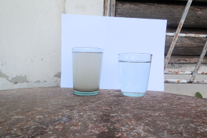 Uno de los vasos (iz) con el agua que se está recibiendo en estos momentos. El otro vaso contiene agua tomada de un tanque plástico de almacenamiento y a pesar de su aparente limpidez es agua no tratada sino suministrada directamente desde el río_foto del autor