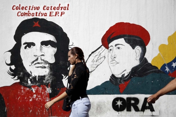 Una mujer pasa frente a un cartel del Che Guevara y Hugo Chávez en Venezuela (Foto: Carlos Garcia Rawlins/Reuters)
