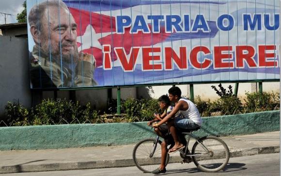 Dos jóvenes pasan en bicicleta frente a un cartel de Fidel Castro (AP)