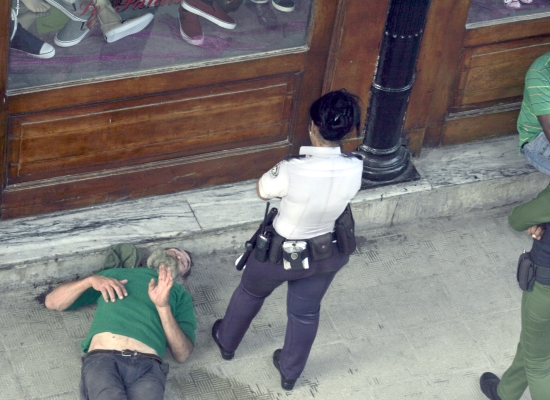 Un hombre mayor de edad, alcoholizado, siendo requerido por una policía frente a una tienda (foto: Ana León)