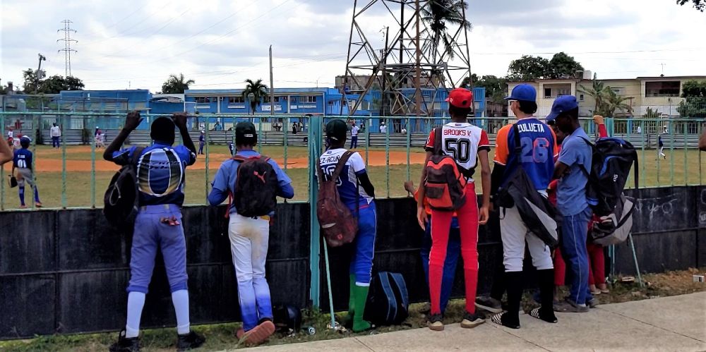 Niños aficionados al béisbol miran un juego de pelota en La Habana